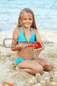 Little girl playing with sand on the beach