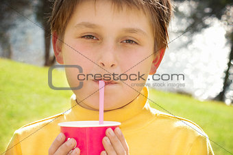 Young boy drinking strawberry milk outdoors