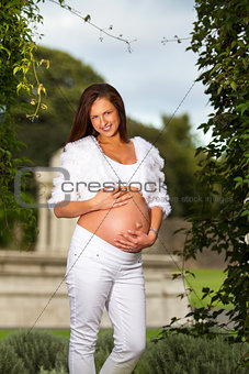 Beautiful pregnant woman standing and touching her belly