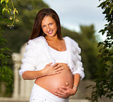 Beautiful pregnant woman standing and touching her belly