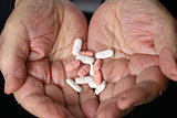 Senior adult holding medicine pill in his hands