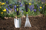 Hand trowel and a rake in garden soil
