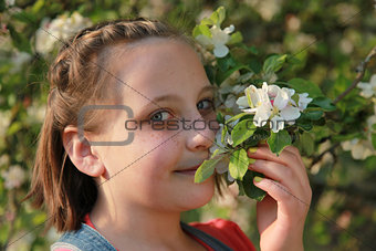 Girl smelling the blossoms of an apple tree