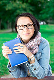 Beautiful young woman with book in park