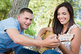 Handsome Young Man Teaching Mixed Race Girl to Play Guitar