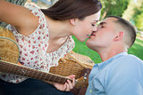 Mixed Race Couple with Guitar Kissing in the Park