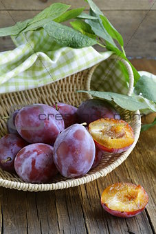 ripe purple plums on a wooden table