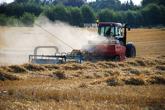 Tractor baling straw in a field