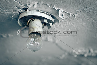 Old light bulb on ceiling of abandoned house