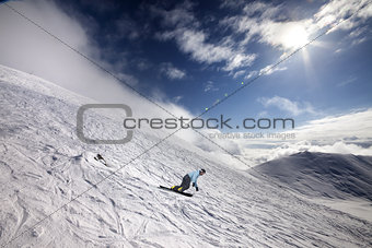 Snowboarder on off-piste ski slope and blue sky with sun