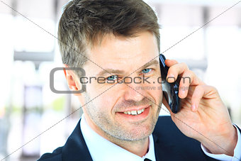 Smiling man using an office phone 