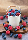 Fresh blueberries and raspberries in a  bucket
