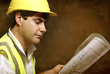 Male builder site foreman reading architectural industrial plans