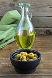 marinated green olives and a bottle of oil on wooden table