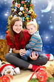 Young woman with a baby near Christmas tree. 