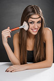 Happy woman applying makeup on her face