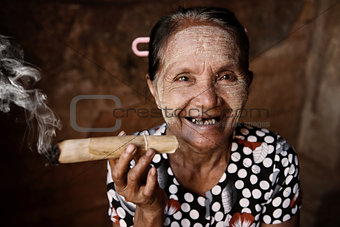 Happy old wrinkled Asian woman smoking 
