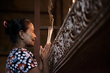Asian woman praying with incense sticks 