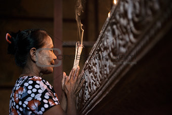 Asian woman praying with incense sticks 