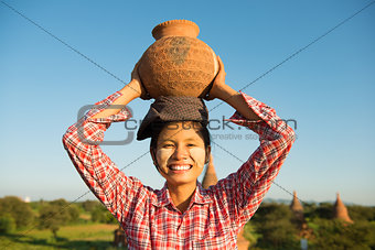 Asian traditional female farmer carrying clay pot