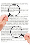 Hands holding magnifying glass reading document