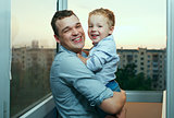 Young father and son smiling on the balcony.