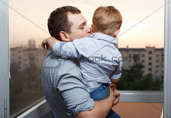 Father kisses his son on the balcony