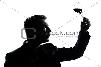 silhouette man tasting  looking at his glass of red wine