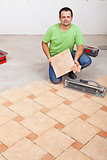 Worker laying floor tiles on concrete surface