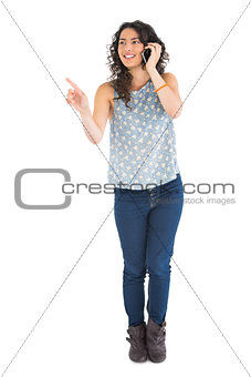 Attractive brunette pointing at something while having phone call