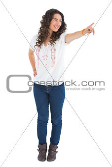 Cheerful attractive brunette wearing casual clothes pointing