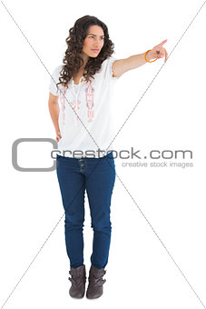 Serious attractive brunette wearing casual clothes pointing