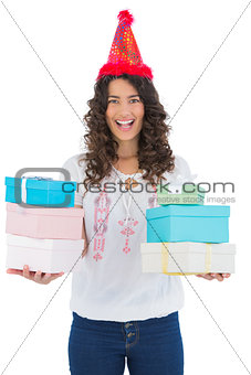 Happy casual brunette wearing party hat holding presents