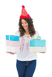 Happy casual brunette with party hat holding presents