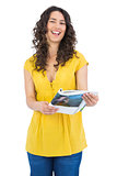 Curly haired brunette laughing while reading magazine