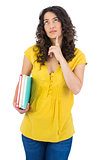 Pensive curly haired student holding notebooks