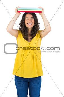 Smiling curly haired student holding notebooks on her head