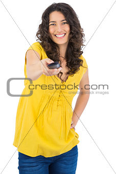 Cheerful curly haired pretty woman holding remote