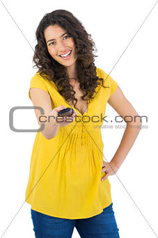 Smiling curly haired pretty woman changing channel with remote