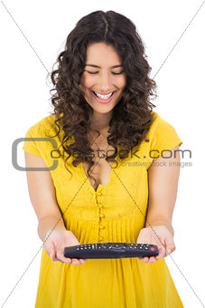 Happy casual young woman holding remote