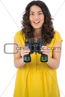 Smiling casual young woman holding binoculars