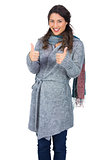 Cheerful pretty brunette wearing winter clothes posing thumb up