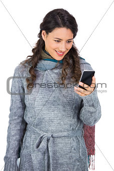 Pretty brunette wearing winter clothes holding her smartphone