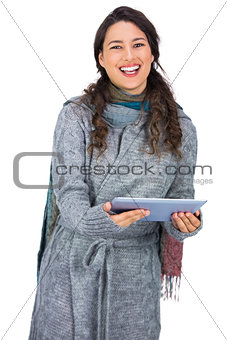 Happy pretty brunette wearing winter clothes holding her tablet