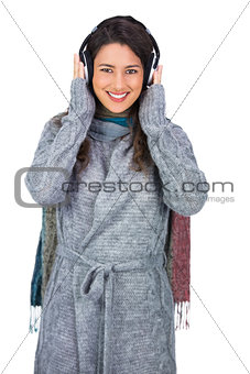 Cheerful beautiful model wearing winter clothes listening to music