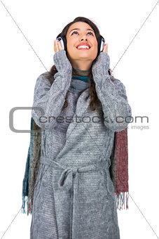 Smiling gorgeous model wearing winter clothes listening to music