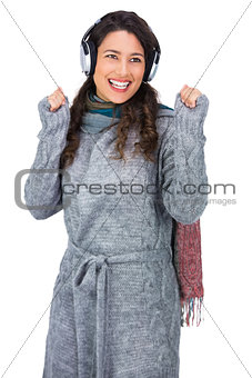 Smiling gorgeous model with winter clothes dancing while listening to music