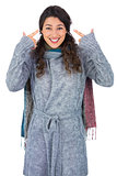 Smiling curly haired model with winter clothes pointing out her head