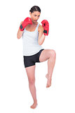 Healthy model with boxing gloves kicking
