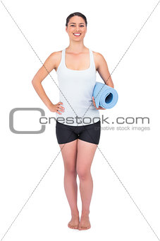 Happy slender model posing holding her rolled up mat